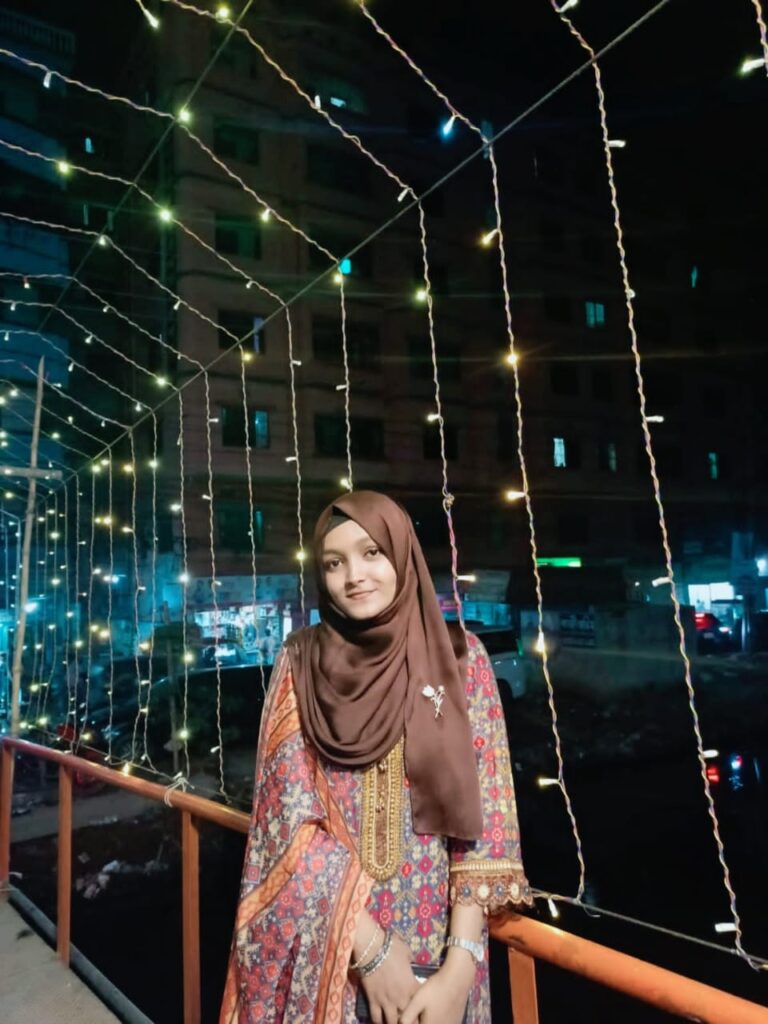 Person standing on a lit walkway at night.